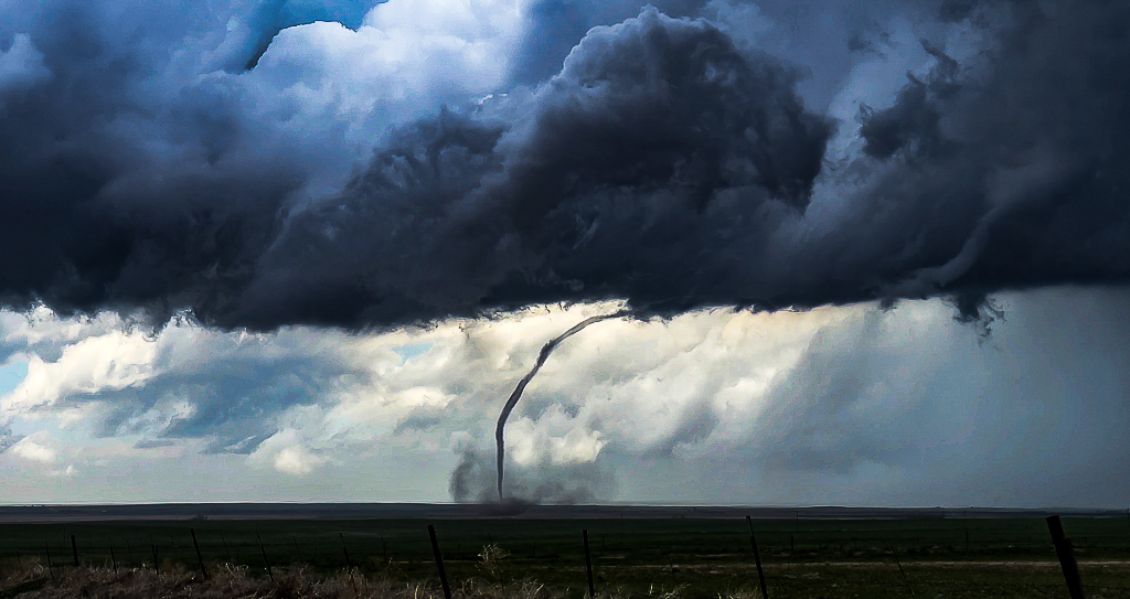 Rope tornado touching down across open plains field