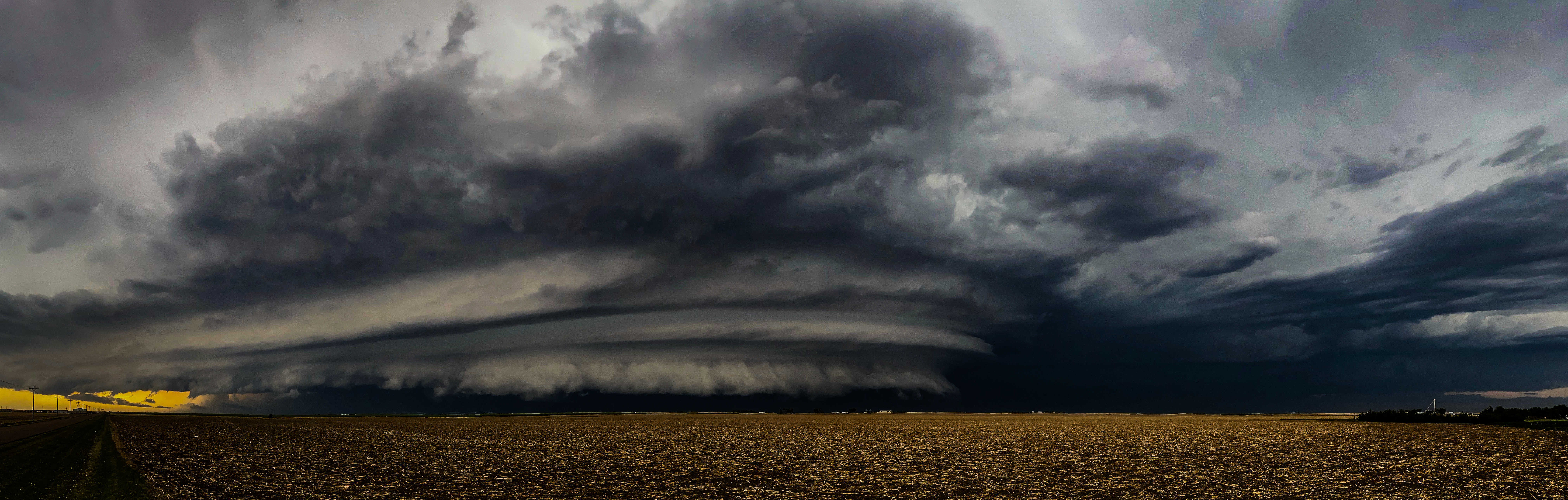 Sculpted supercell structure lit by golden hour sunset over wheat stubble
